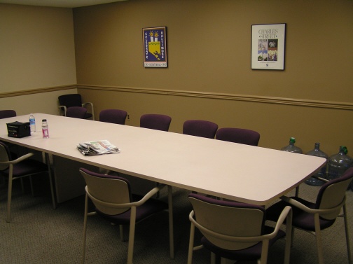 I sit in the middle chair on the facing side, under the purple poster.